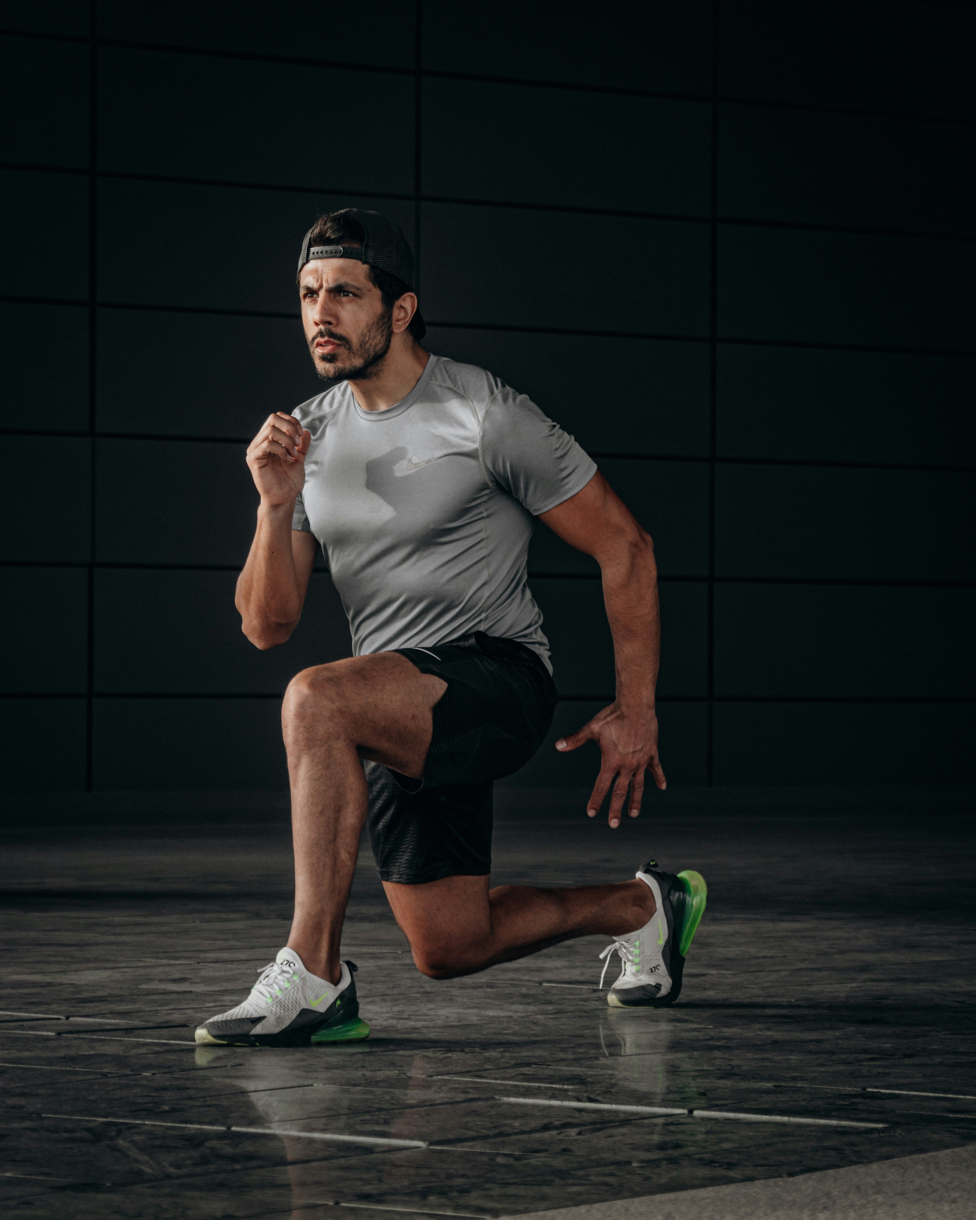 Man in athletic wear performing a lunge on a dark background